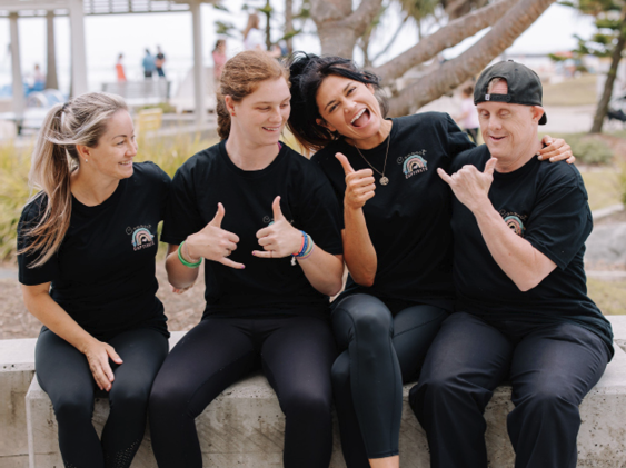 A group of people communicating in a park together. They are smiling and laughing.