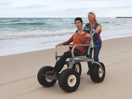 A person with disability being supported to access the beach.