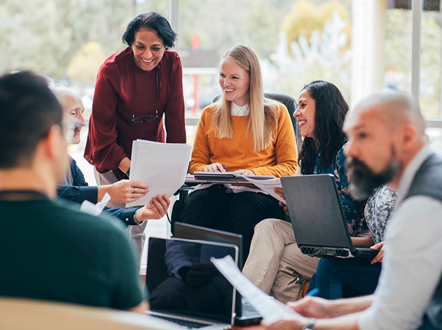 A group of people working together on documents and laptops.